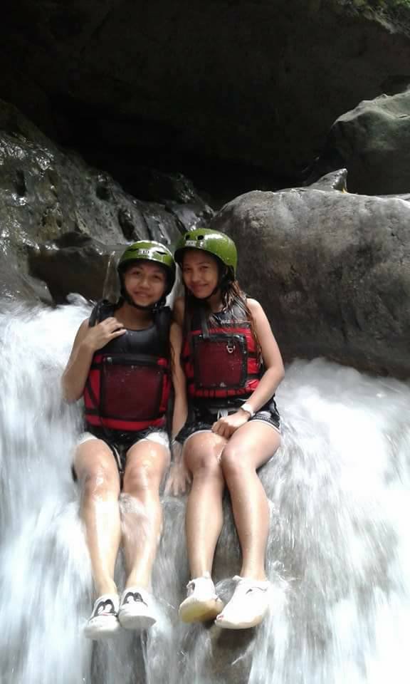 Two girls wearing green helmet and red life jacket during Kawasan Canyoneering Tour for safety.