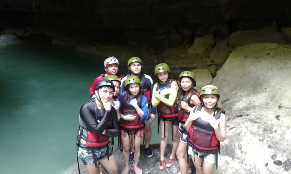 The people standing at the top of the rock wearing life jacket and helmet during Kawasan Canyoneering Tour.